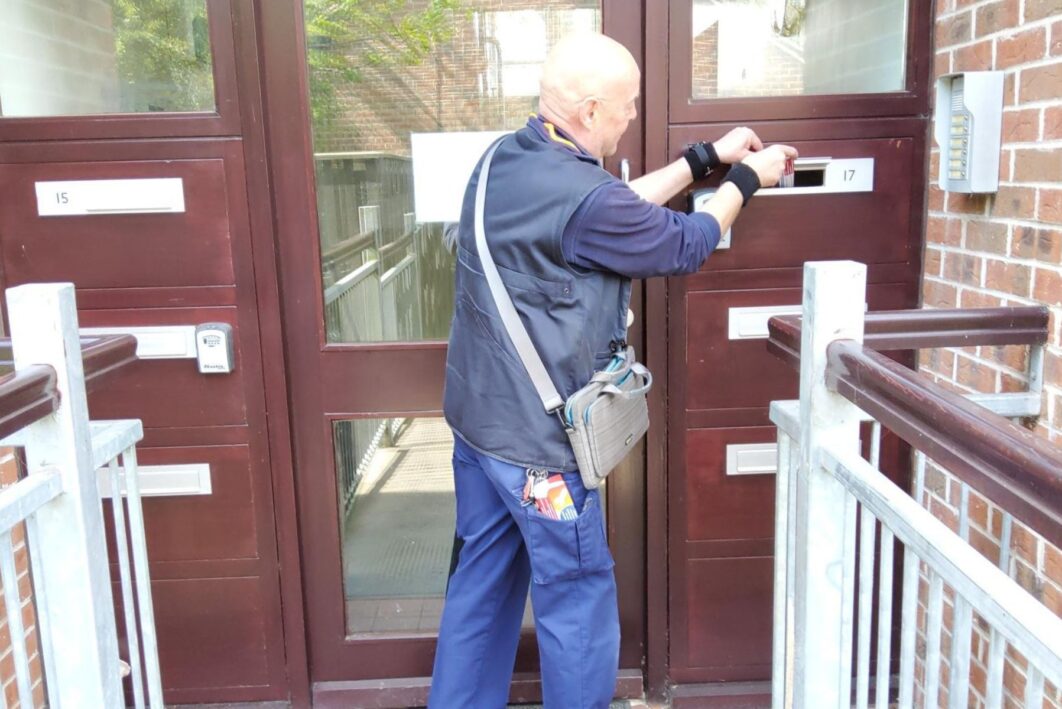 A man delivering a fire safety leaflet through a post box
