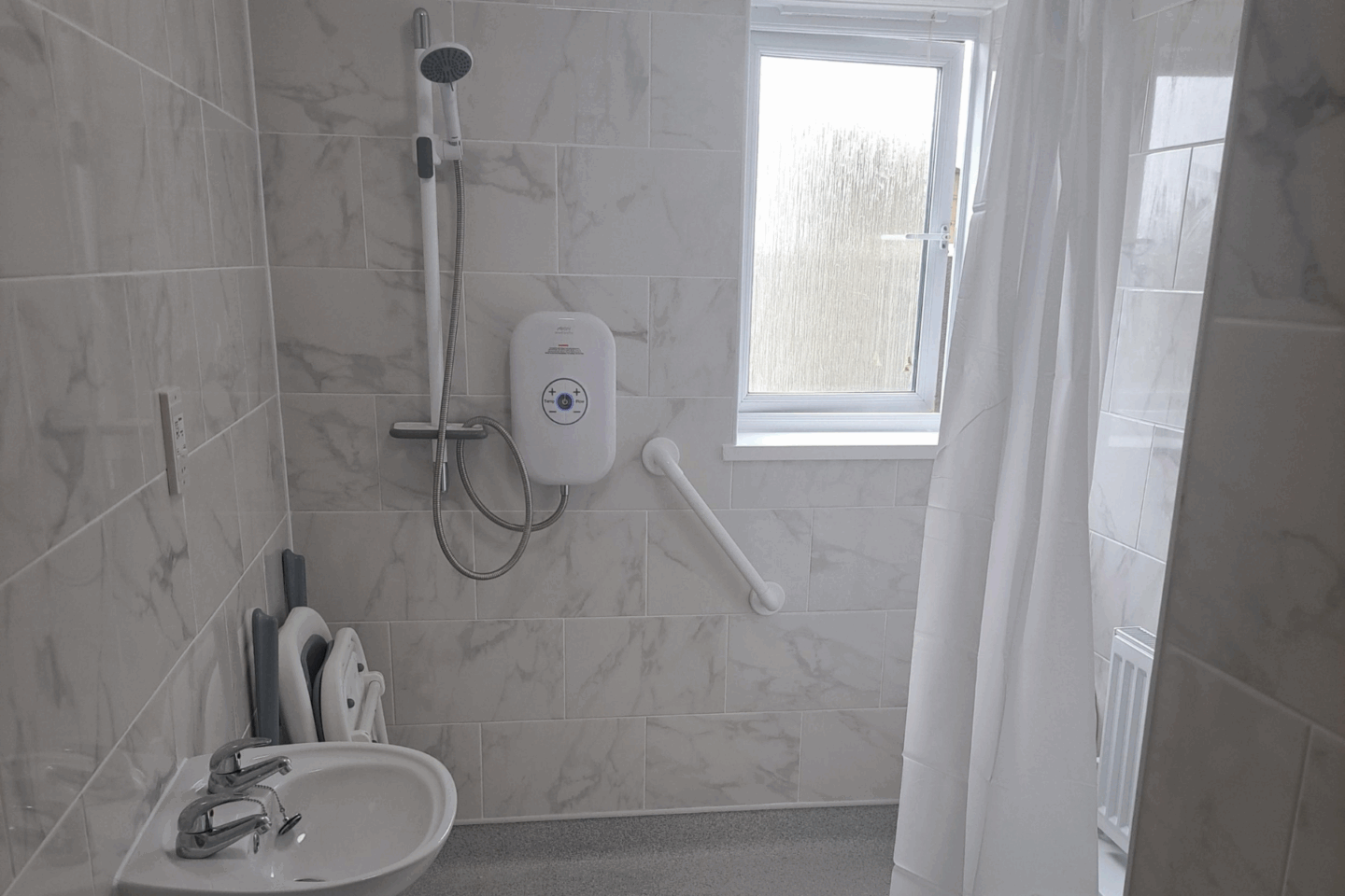 Wetroom showing grabrails, shower curtain and shower chair
