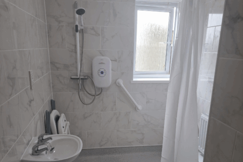 Wetroom showing grabrails, shower curtain and shower chair
