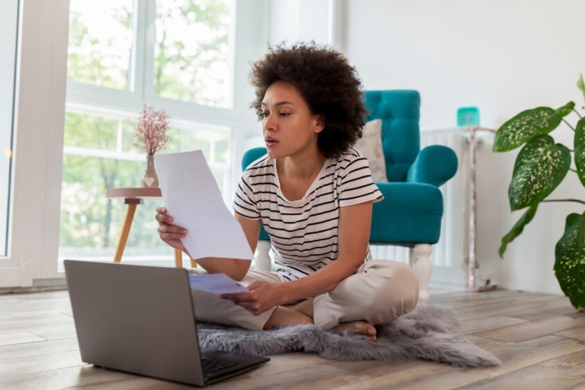 Woman looking at paper in front of laptop