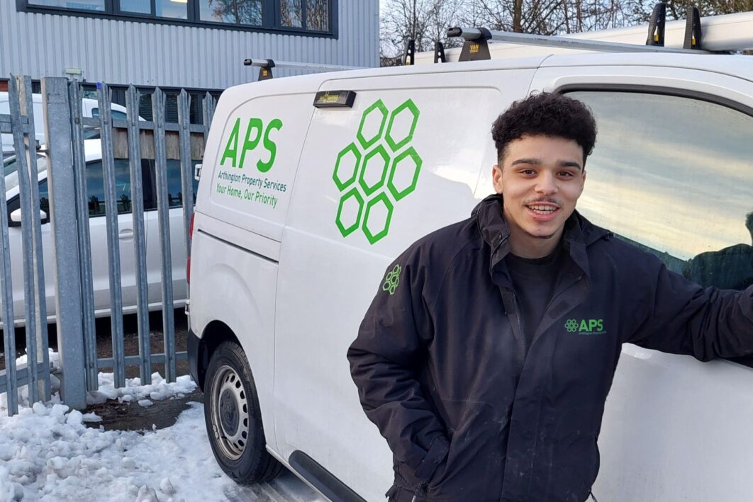 A man stood in front of a van that says APS on it.