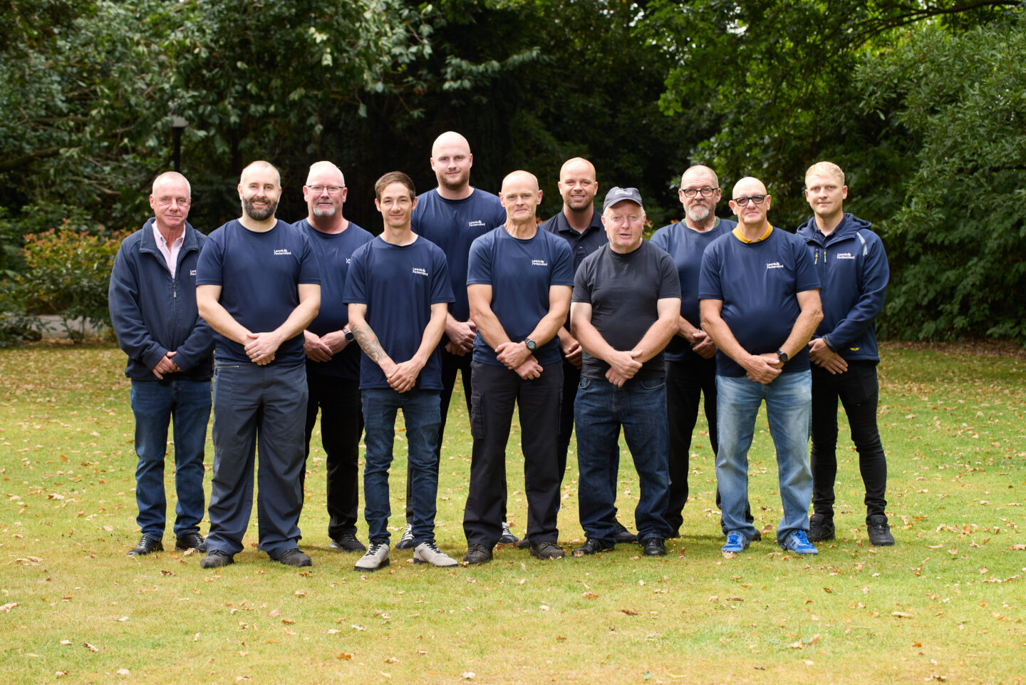 Community Spaces team standing on a lawn together. They are smiling. There are trees in the background.