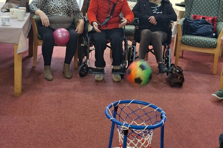 People sat in a row throwing a ball into a net
