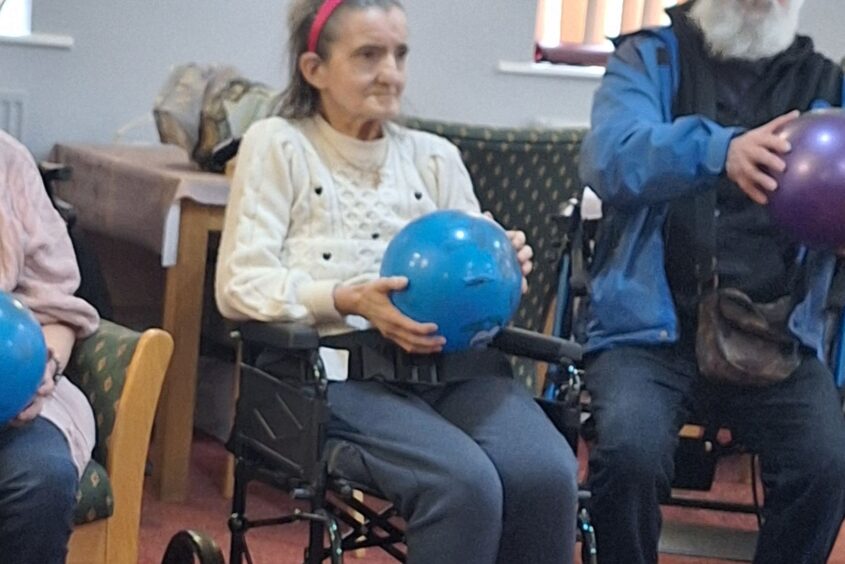 A woman sat in a wheelchair holding a ball