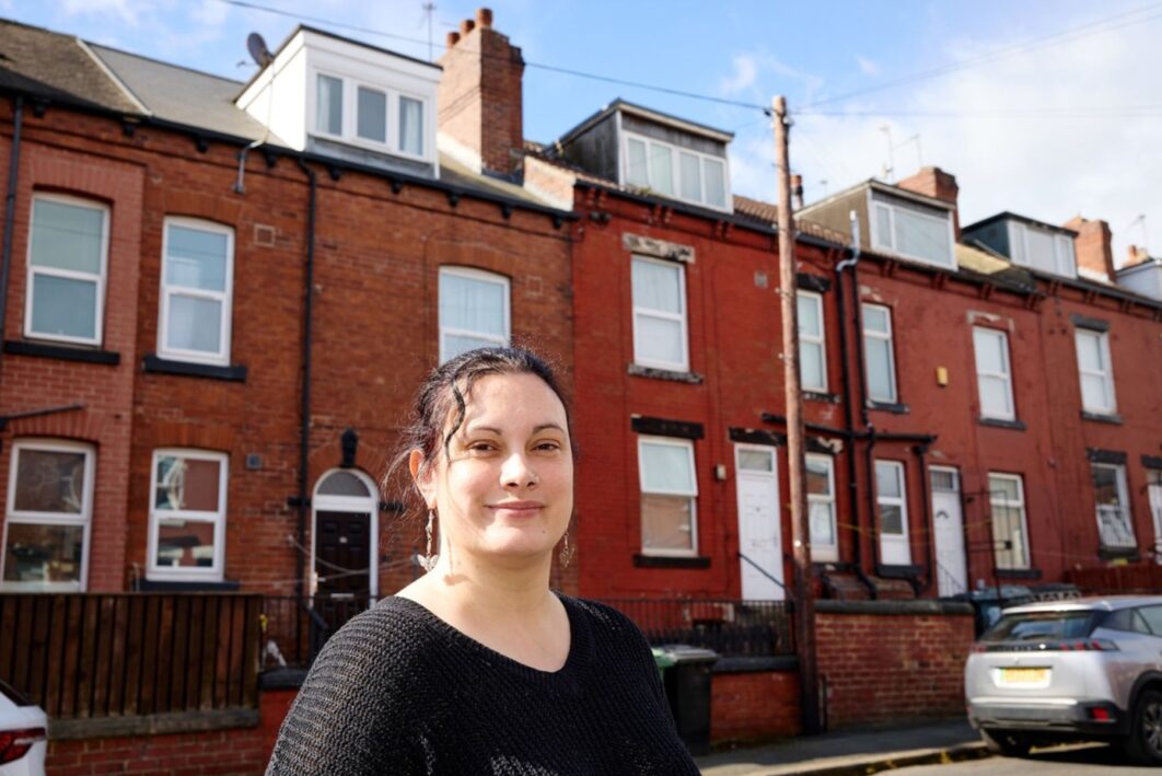Woman stood in front of a row of terrace houses