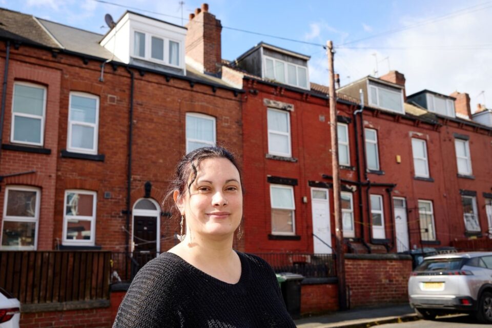 Woman stood in front of a row of terrace houses