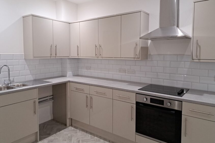 Brand new kitchen with grey wall and floor units and white metro wall tiles