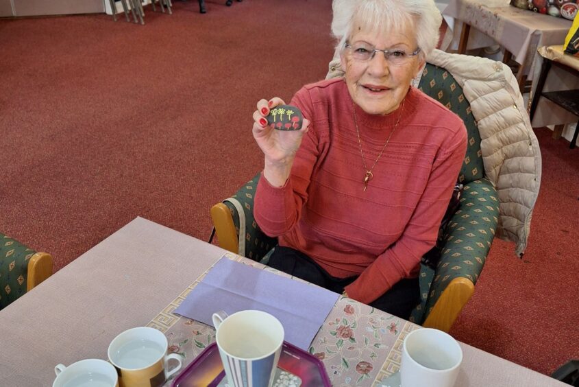 An elderly lady holding a pebble that she has painted