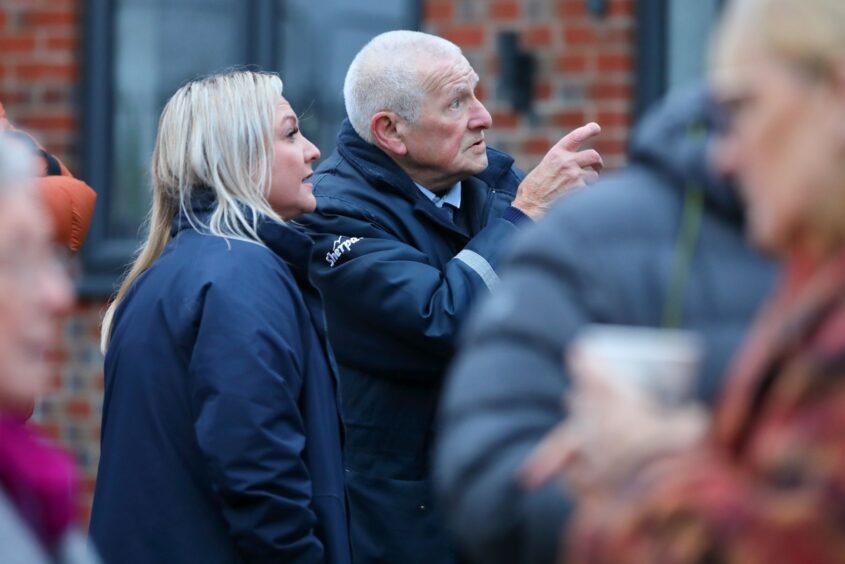 Two people pointing and looking to the right