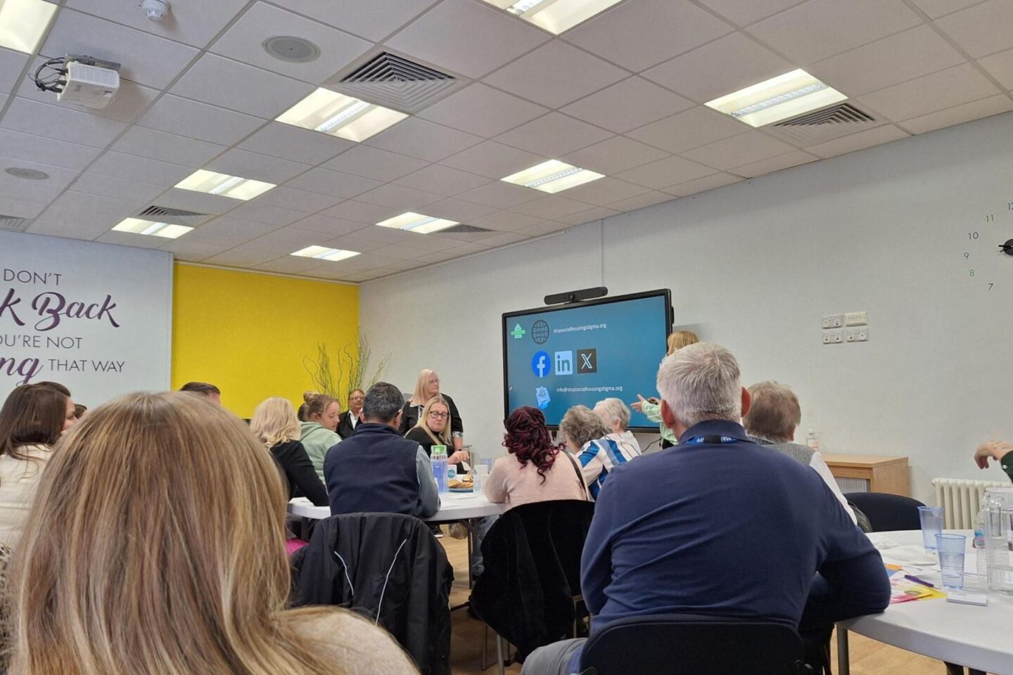 People sitting at people watching a presentation at the front of the room