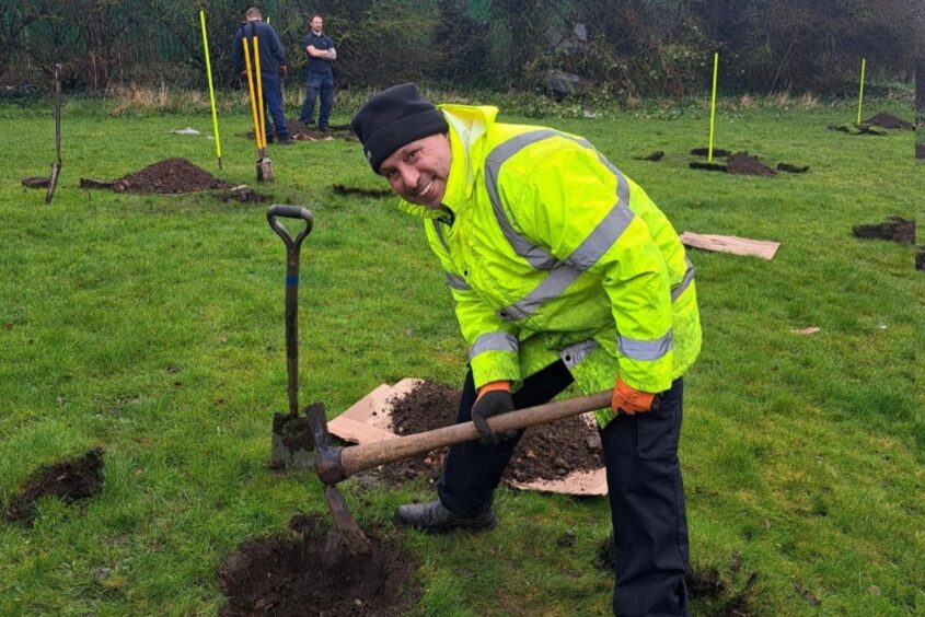 A man digging in soil planting a tree