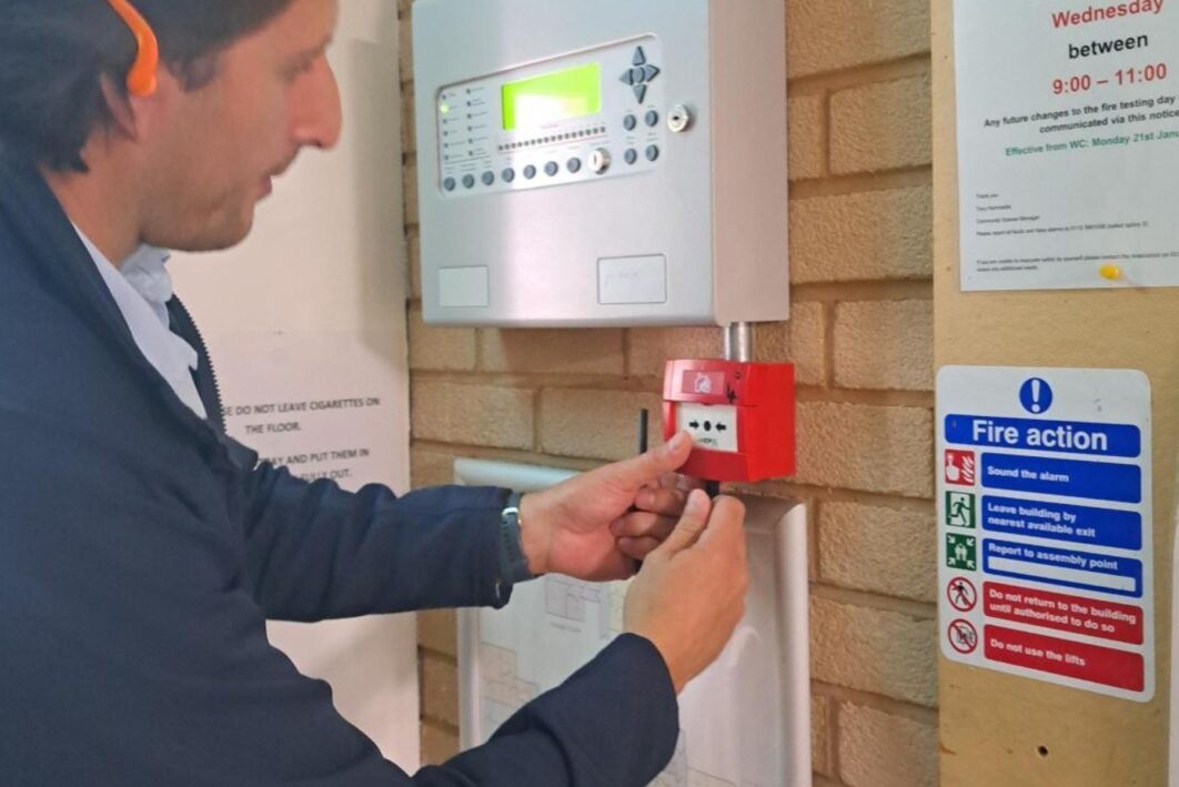 Man testing a fire alarm, wearing ear protectors