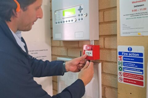 Man testing a fire alarm, wearing ear protectors