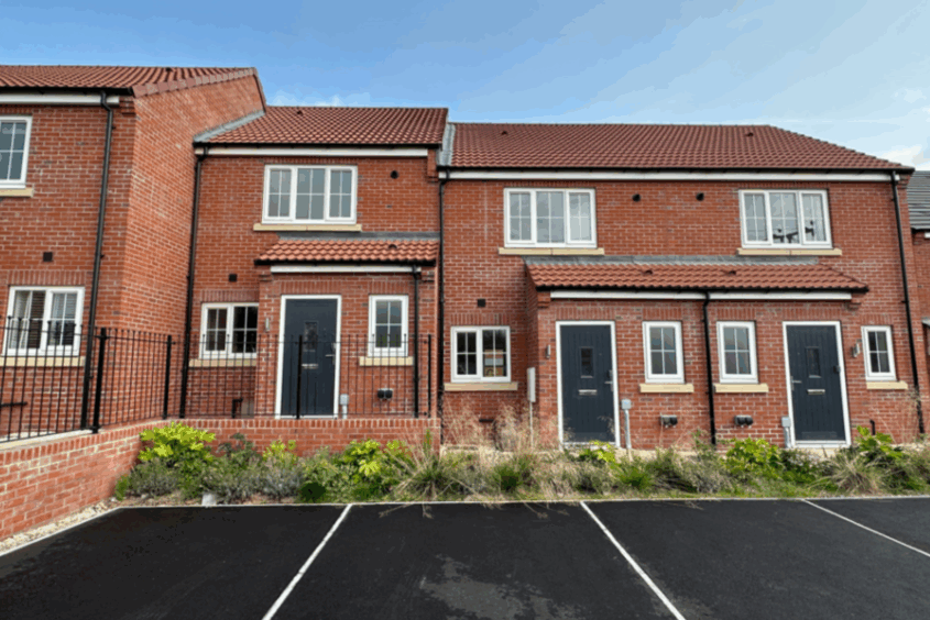 Row of red brick homes with shrubs and drives to the front