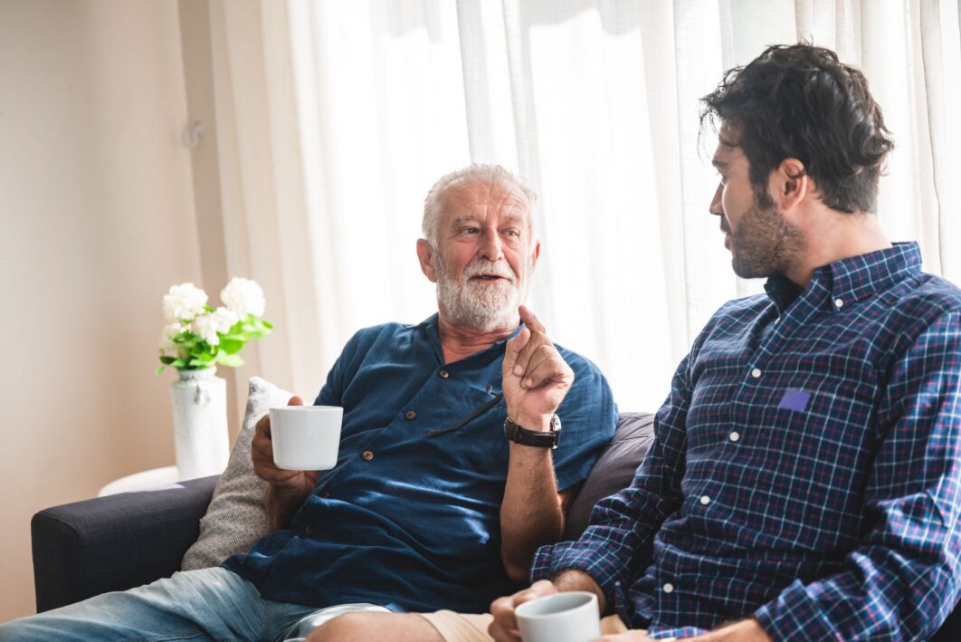 Two men sat talking on a sofa