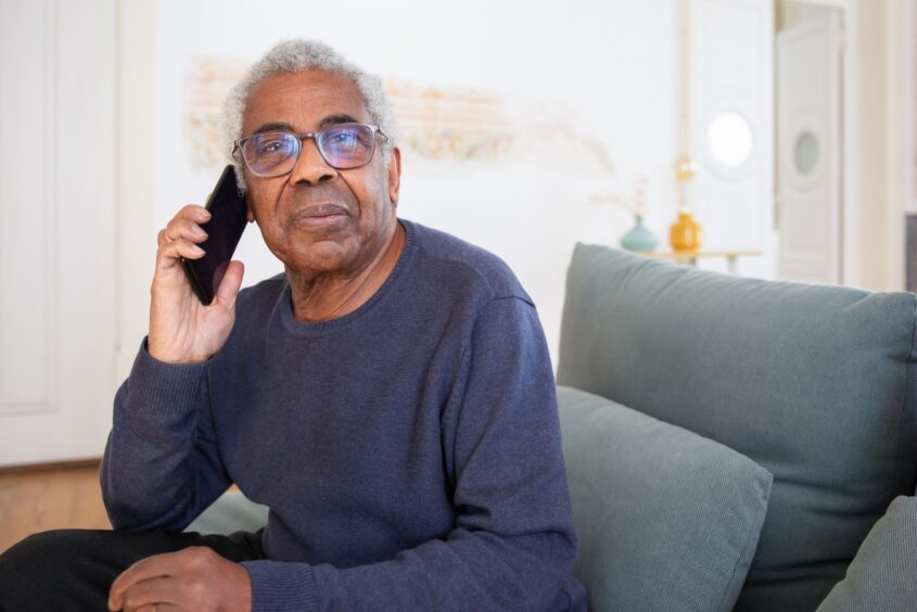 An older man talking on the phone at home