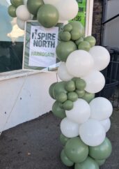 Balloon arch with Inspire North poster.
