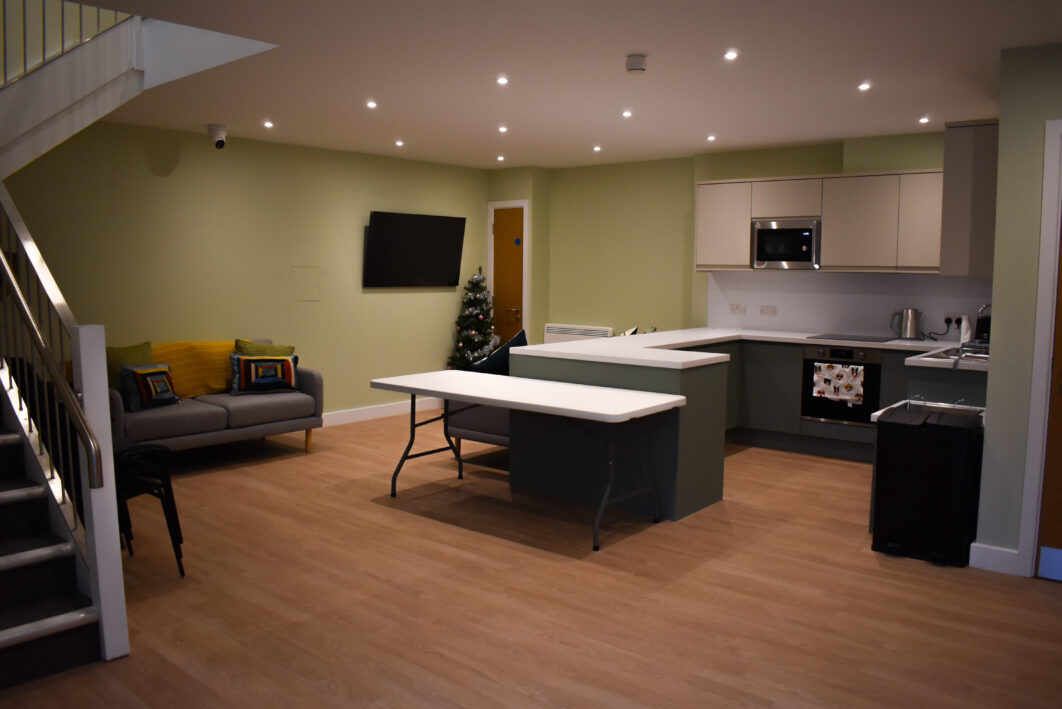 A kitchen with a sofa and a TV on the wall