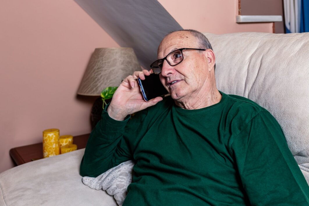 Man sat on the sofa talking on the phone