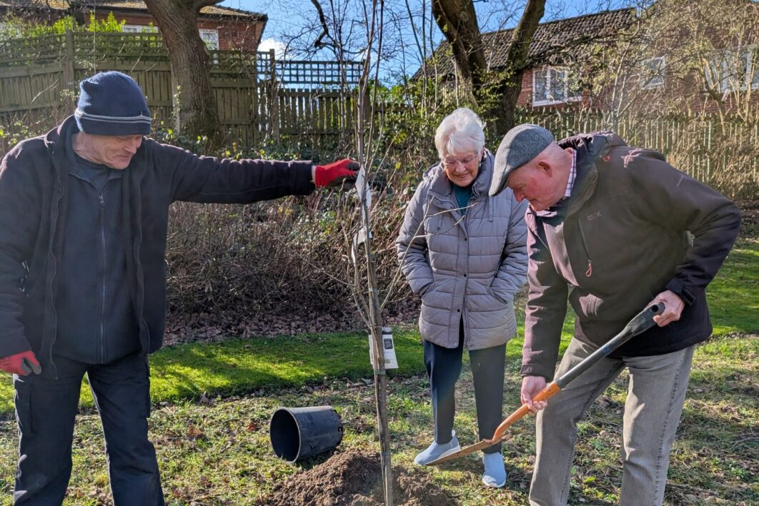 Residents planting tree with gardener