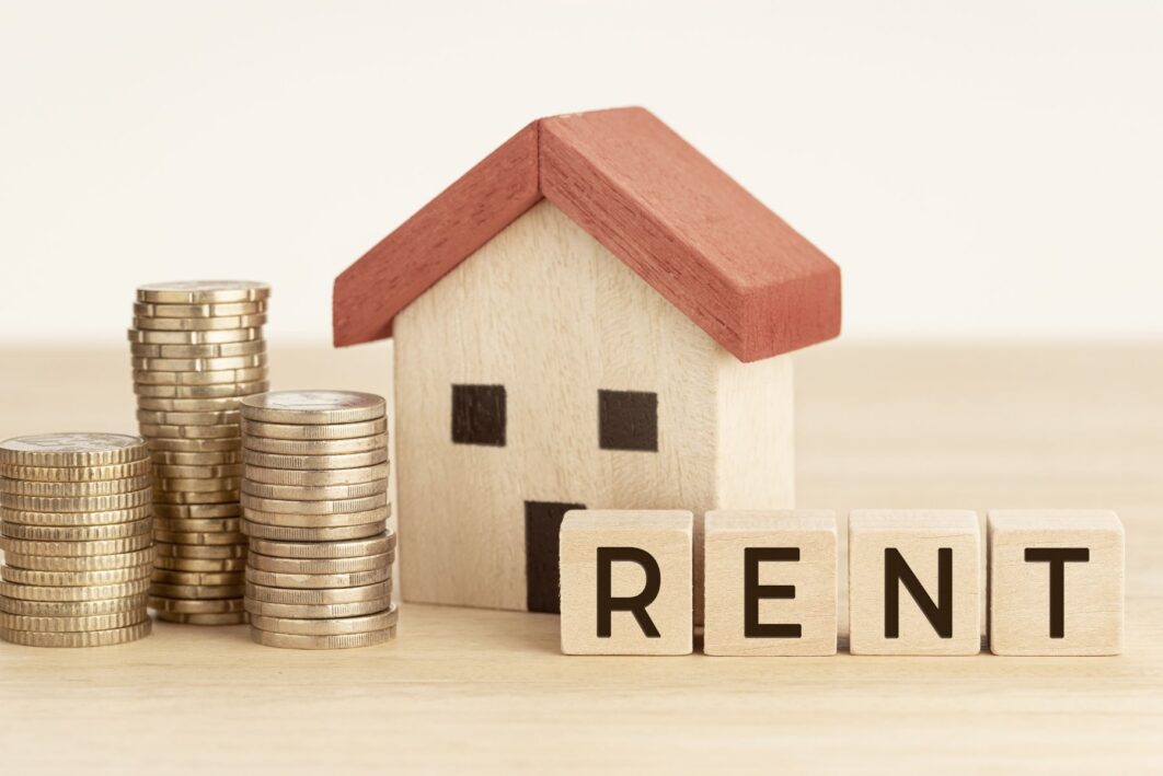 Graphic image of a wooden house with pennies next to it and a blocks that spell 'rent'