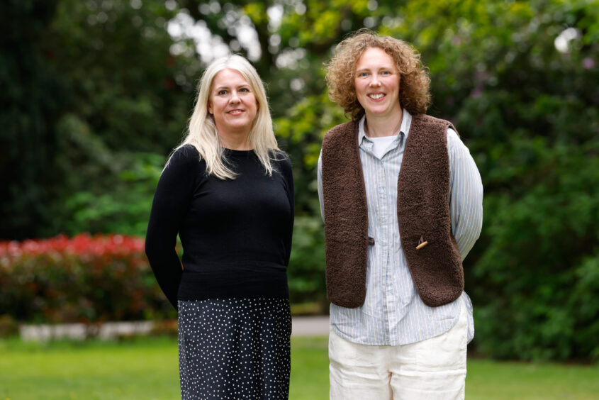 Two members of the Customer Engagement team standing in a garden area, smiling.