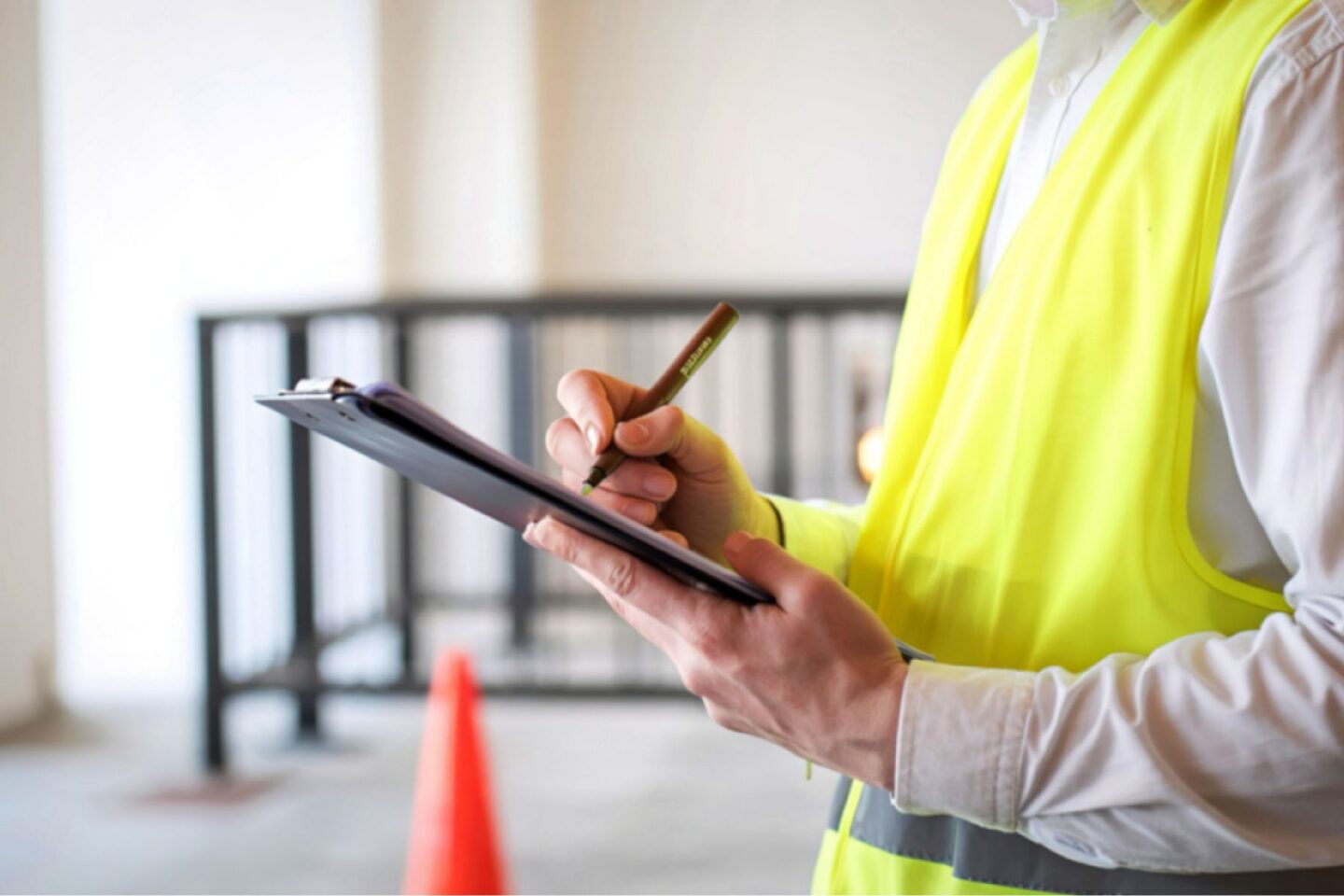 a surveyor holding a clipboard and wearing a high vis vest