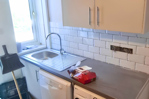Tiling being finished above the kitchen worktops