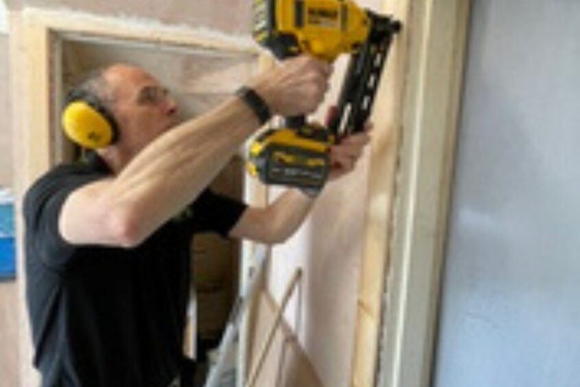Jason using electric drill on a door frame.