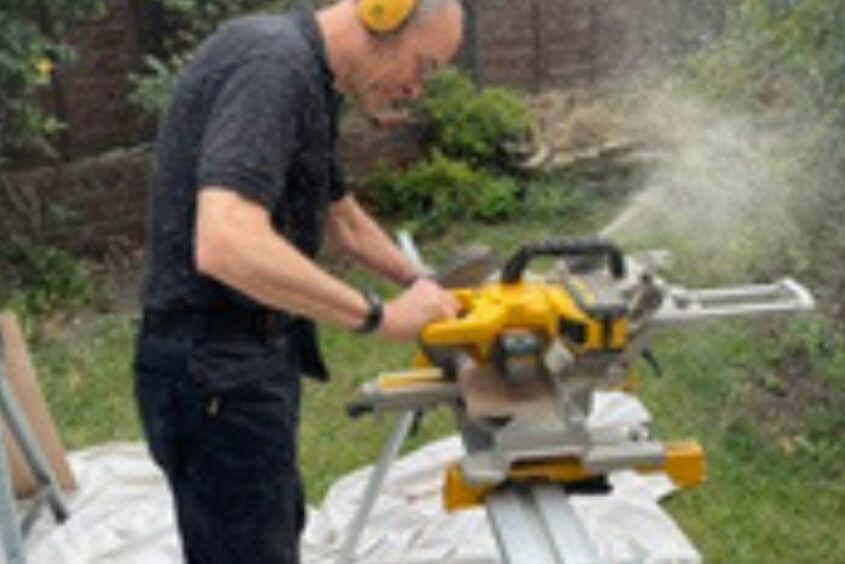 Jason using a saw wearing ear protectors.